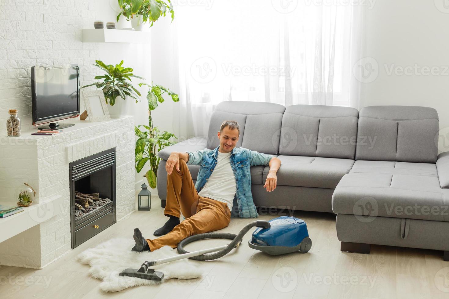 Un joven limpia el sofá con una aspiradora.