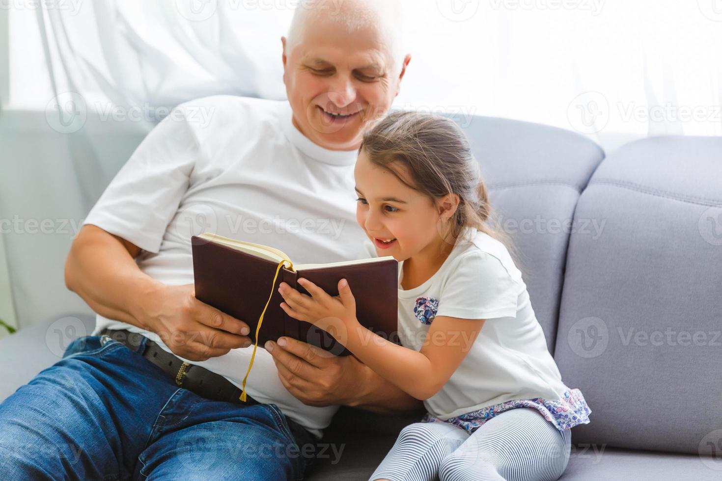 niña feliz con el abuelo leyendo un libro de cuentos en casa foto