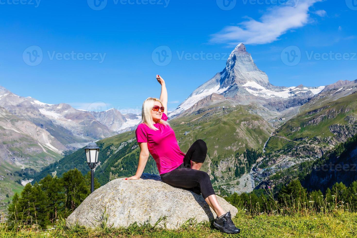 Young girl holds hands up against the sky and mountain photo
