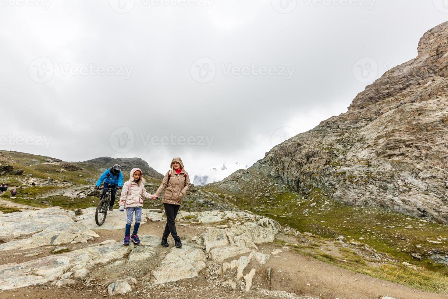 Mother and to children going for a walk in mountain surroundings photo