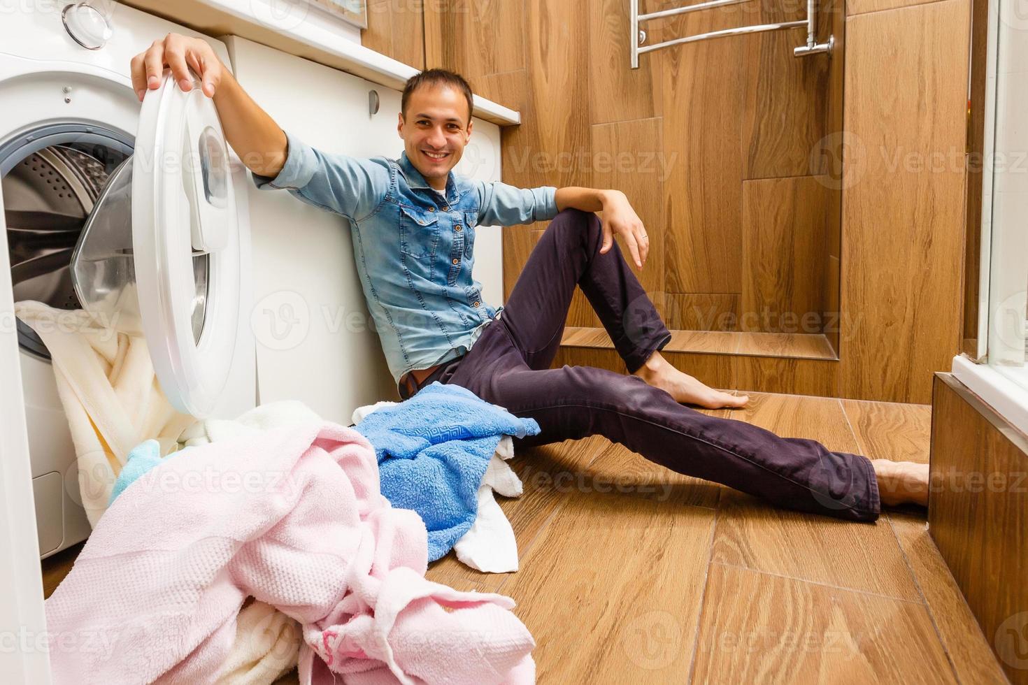 Man loading cloths to washing machine. View from inside the washing machine. photo