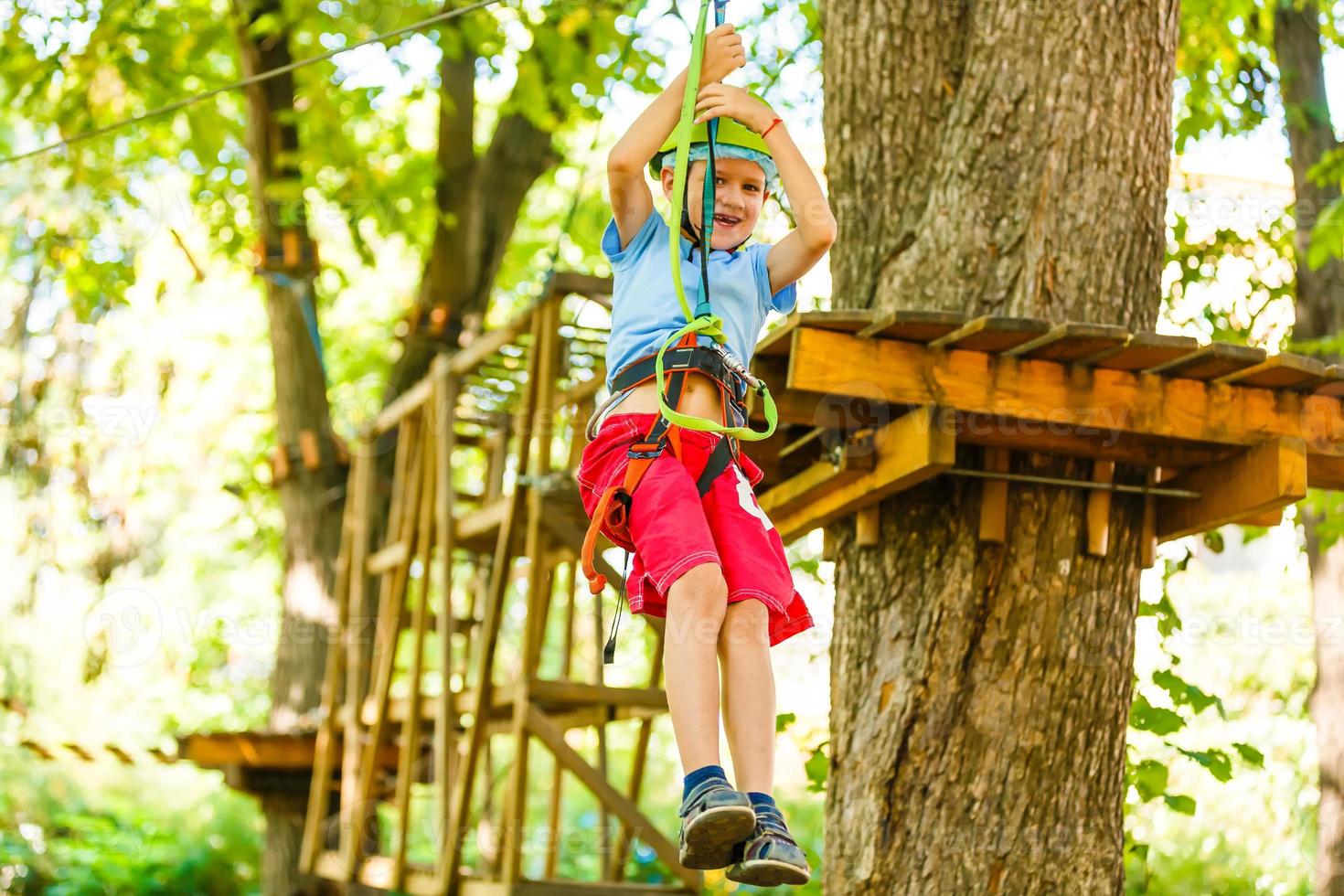 parque de cuerdas de escalada de aventura - niños en el parque de cuerdas del curso en casco de montaña y equipo de seguridad foto