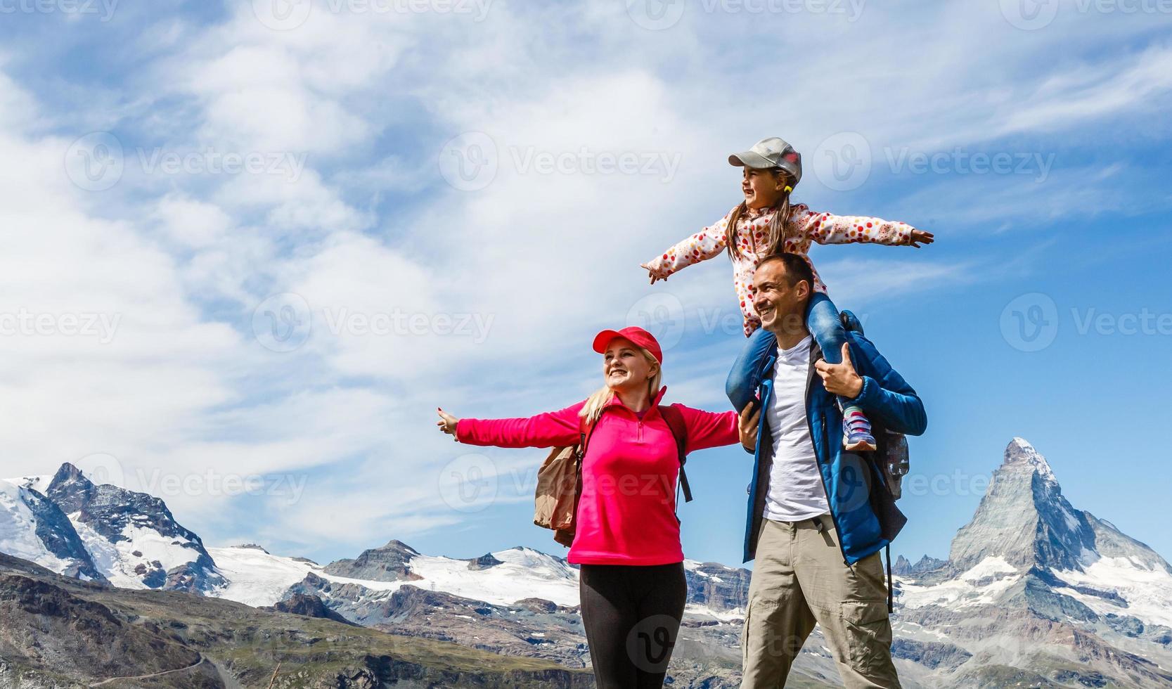 Happy family with little child doing trekking on switzerland mountain in summer time. Young people having fun in landscape nature. Concept of travel, friendly family photo