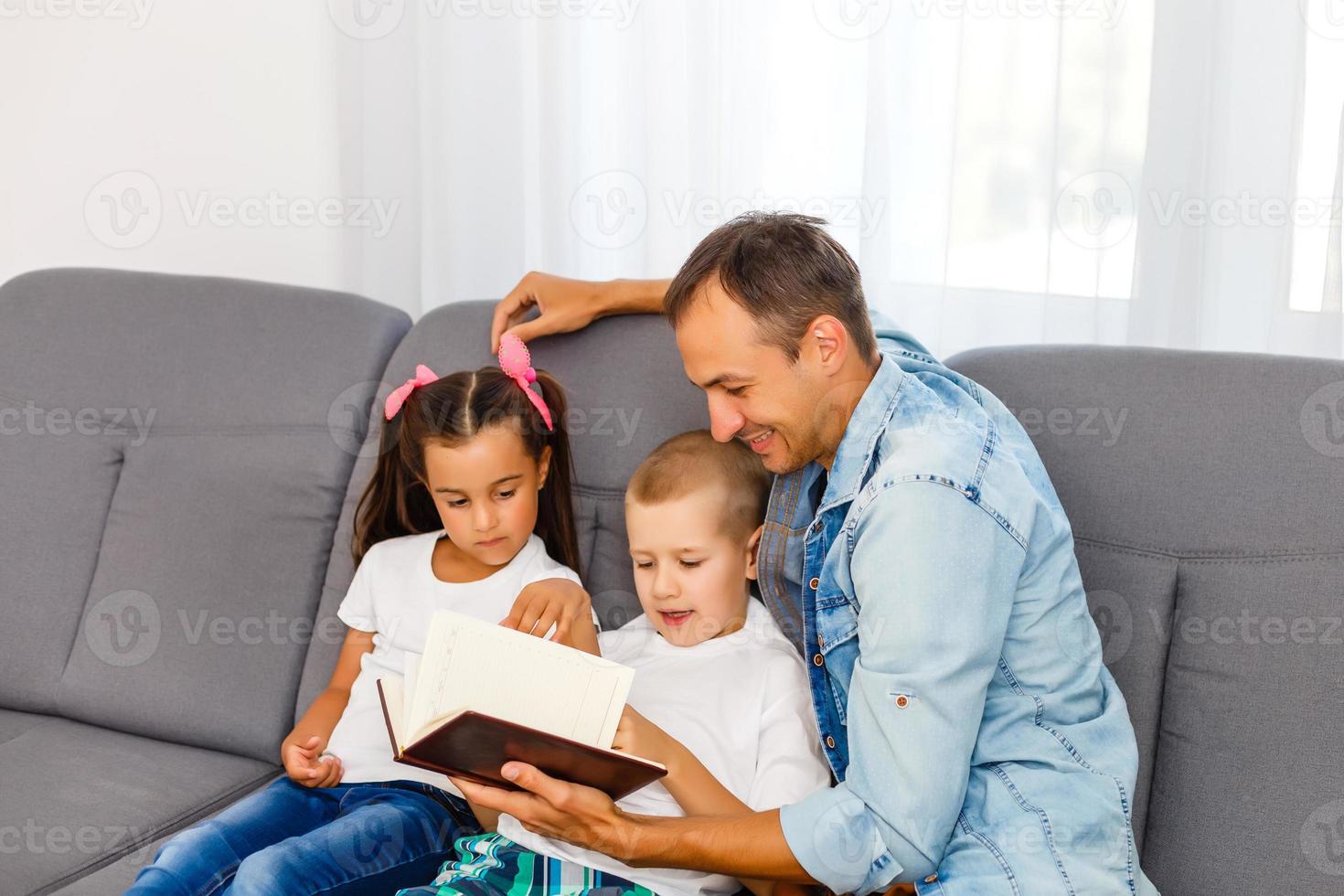 Young father reading book to little children photo