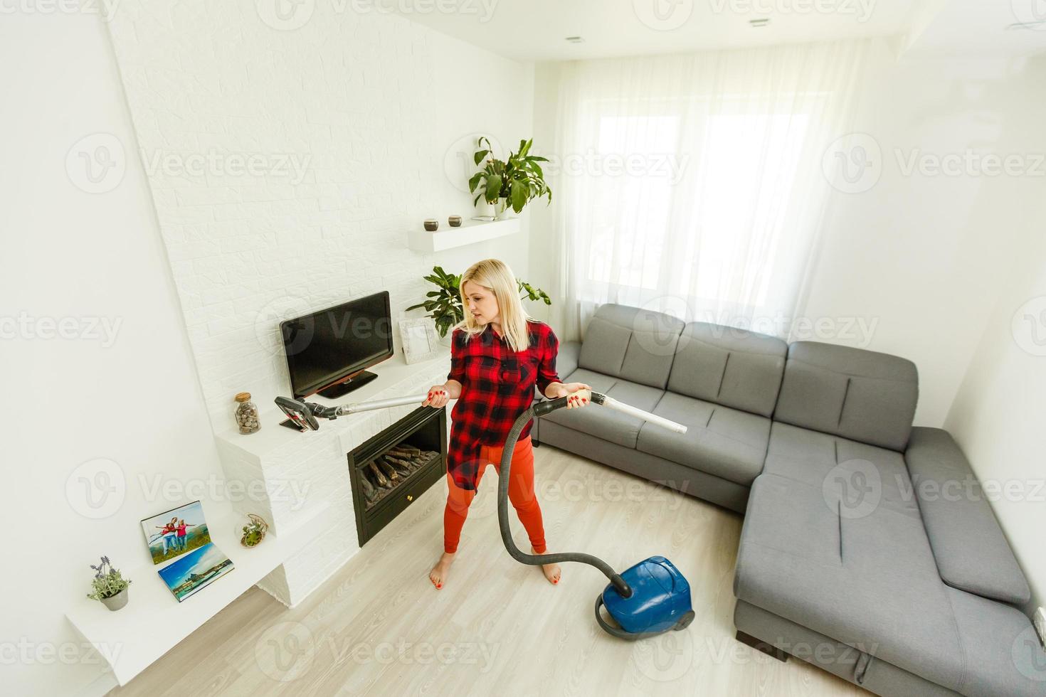 Portrait of happy young female in t-shirt with vacuum cleaner in the modern photo
