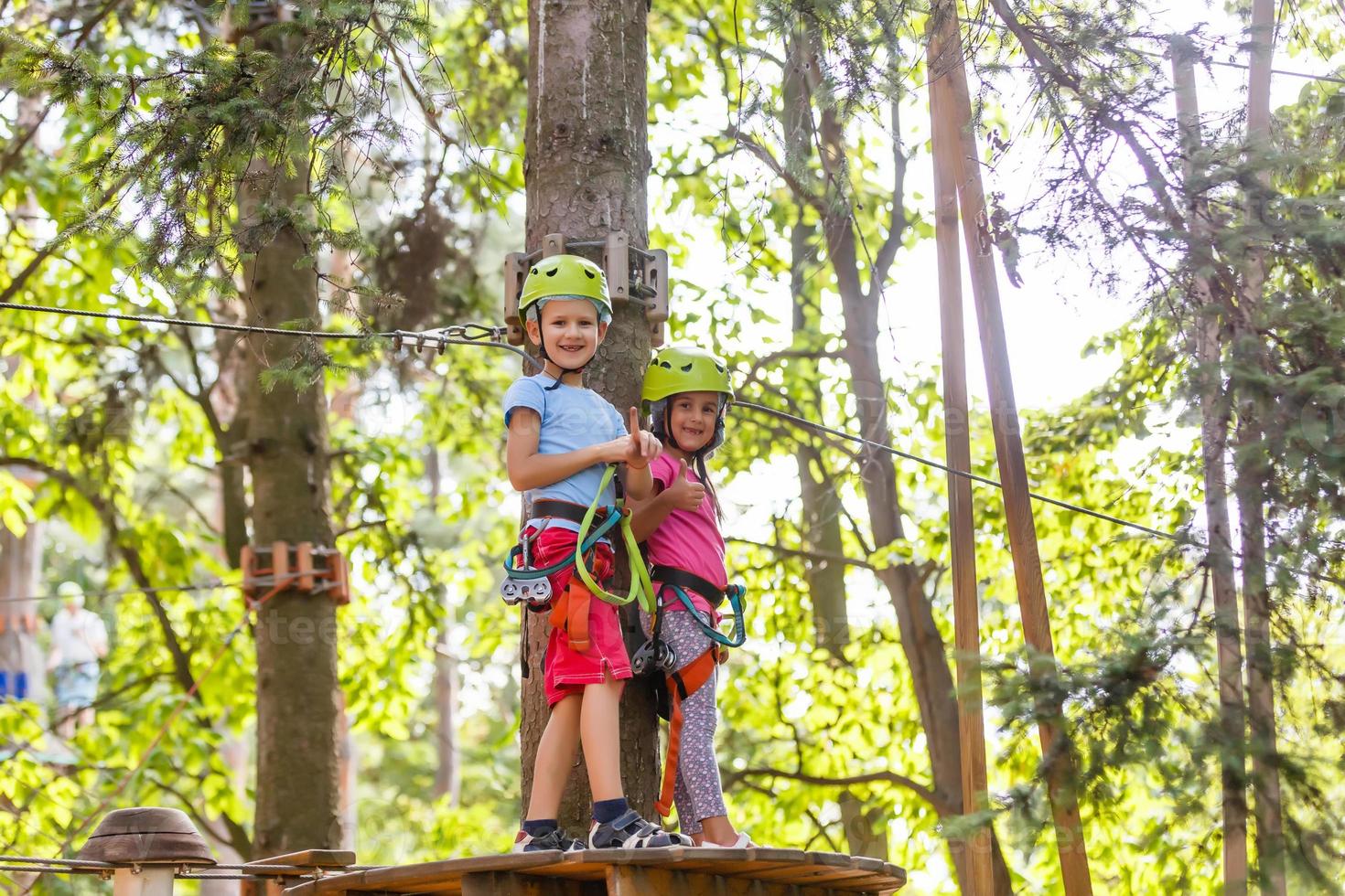 parque de cuerdas de escalada de aventura - niños en el parque de cuerdas del curso en casco de montaña y equipo de seguridad foto