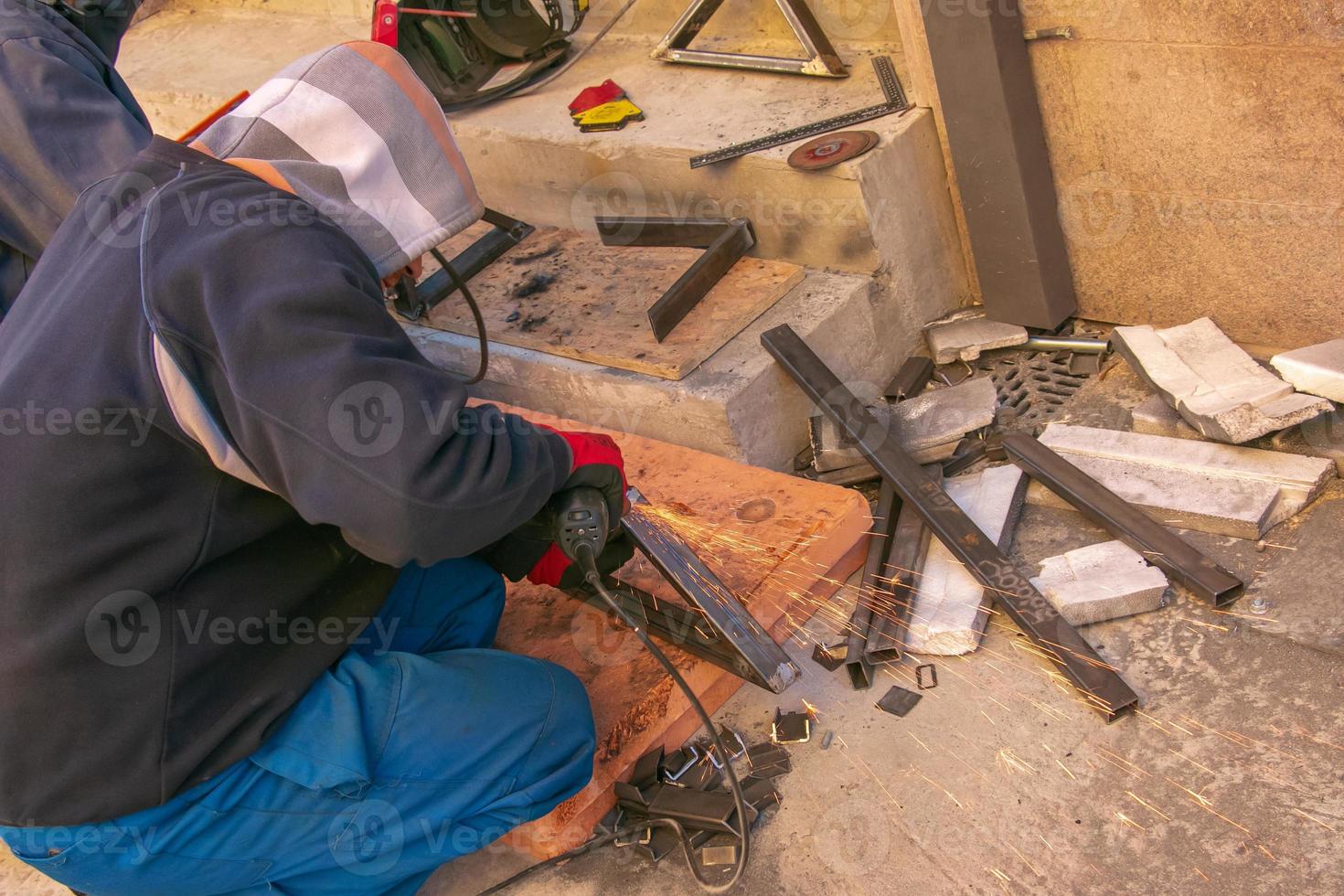 Man working with grinder saw, close up view on tool. Electric saw and hands of worker with sparks. Worker cutting metal with grinder. photo