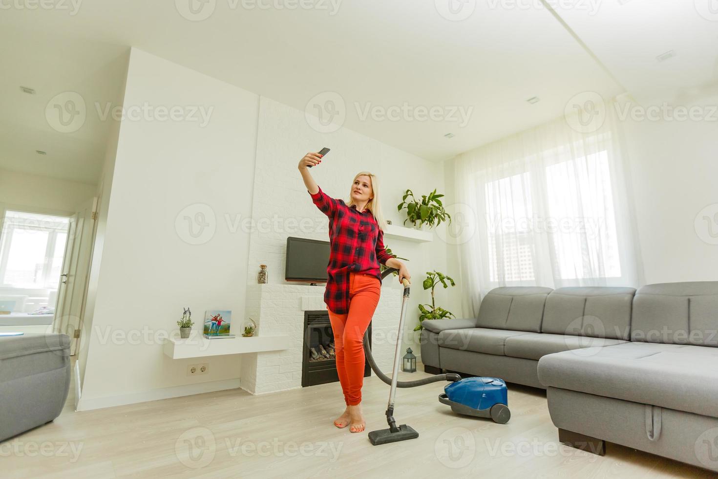Portrait of happy young female in t-shirt with vacuum cleaner in the modern photo