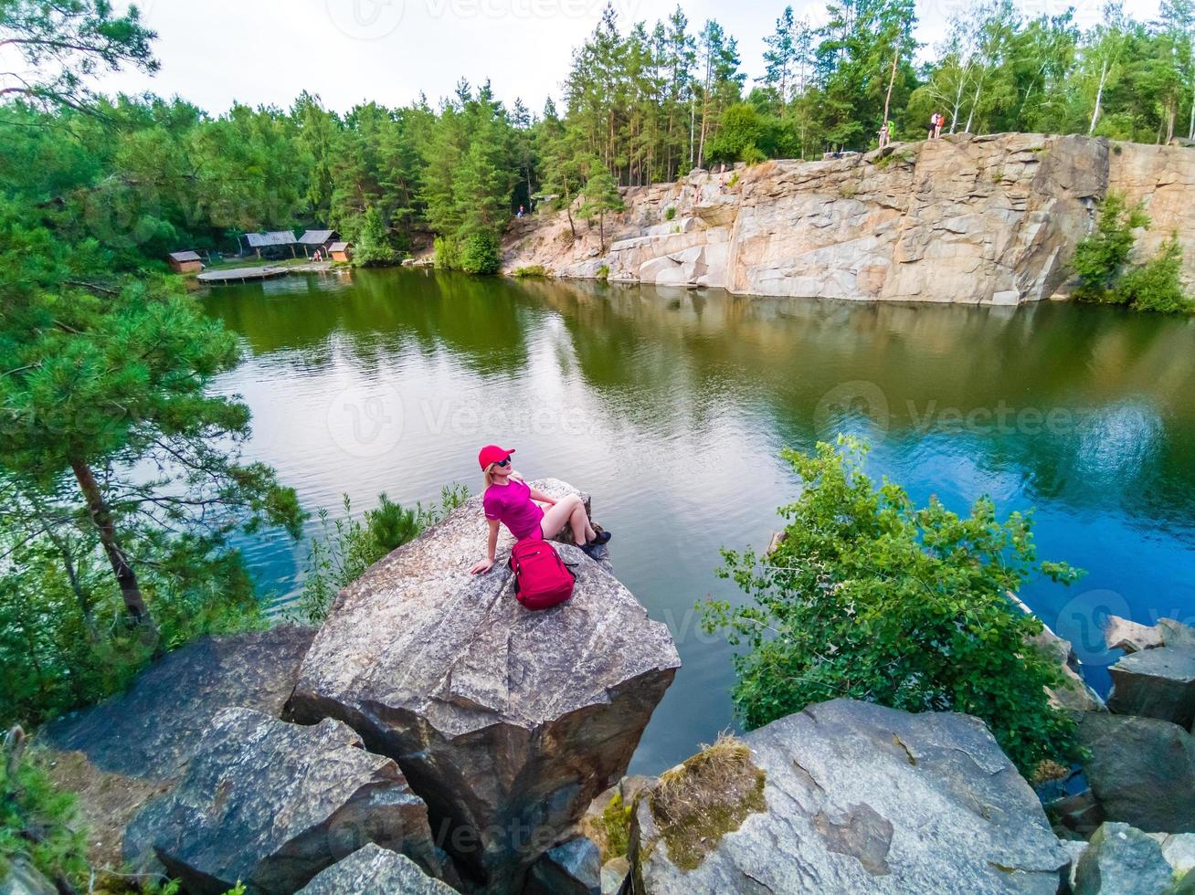 Hiker with backpack relaxing on a rock and enjoying sunset photo