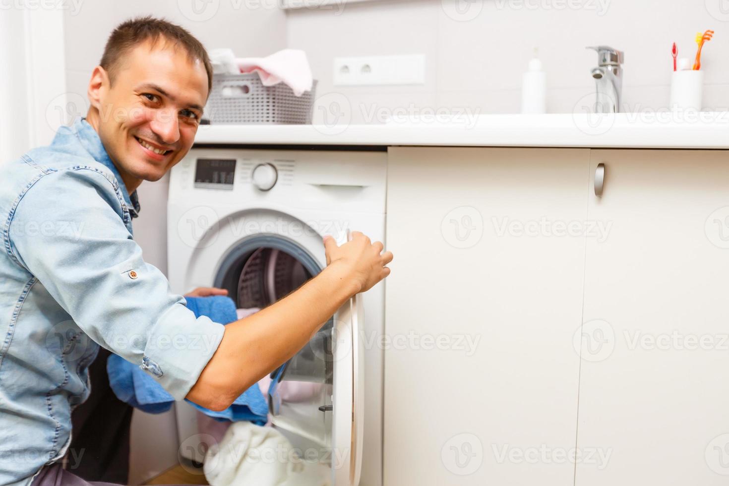 Man loading cloths to washing machine. View from inside the washing machine. photo
