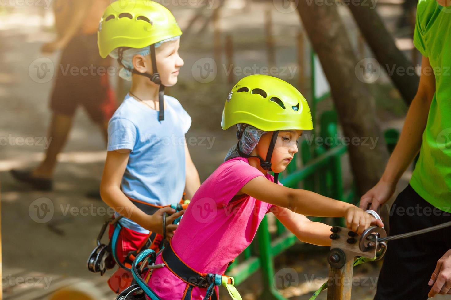 adventure climbing high wire park - children on course rope park in mountain helmet and safety equipment photo