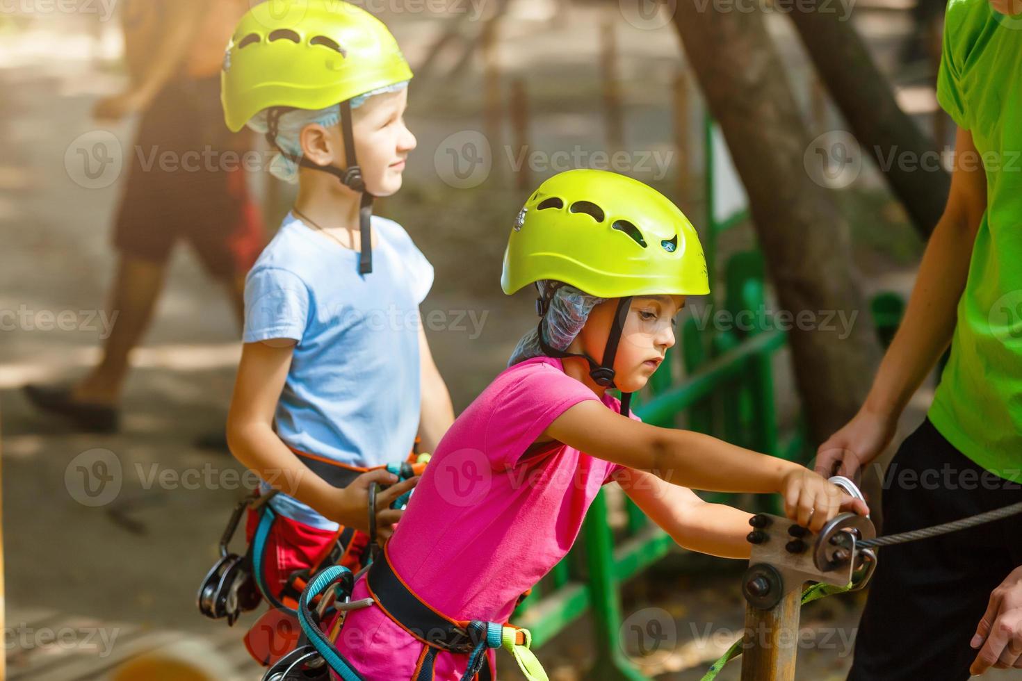 parque de cuerdas de escalada de aventura - niños en el parque de cuerdas del curso en casco de montaña y equipo de seguridad foto