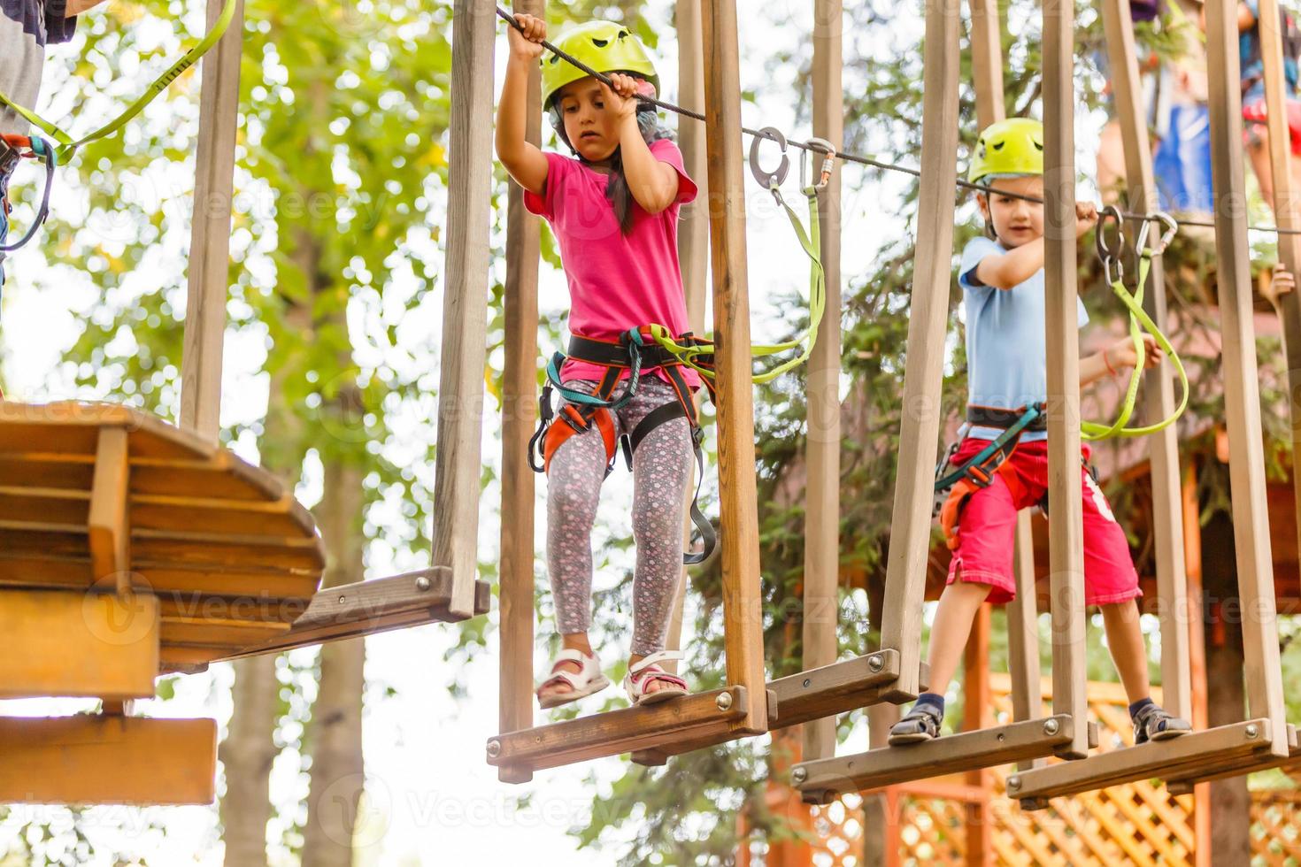 parque de cuerdas de escalada de aventura - niños en el parque de cuerdas del curso en casco de montaña y equipo de seguridad foto