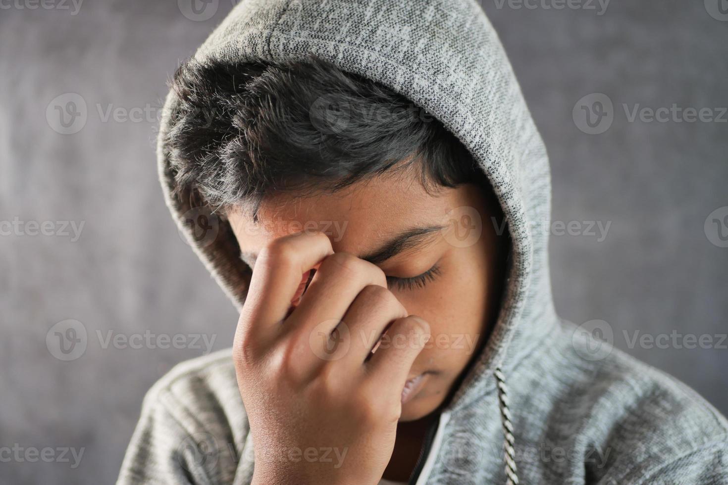 sad teenage boy covering his face sitting on sofa photo