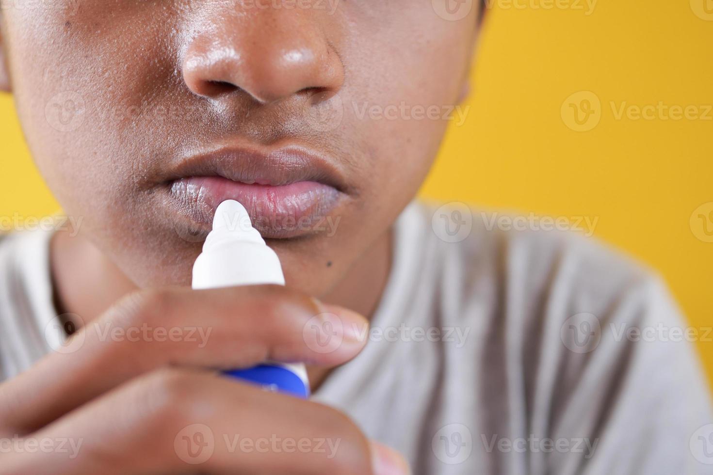 young man applying moisturising lip balm on lips photo