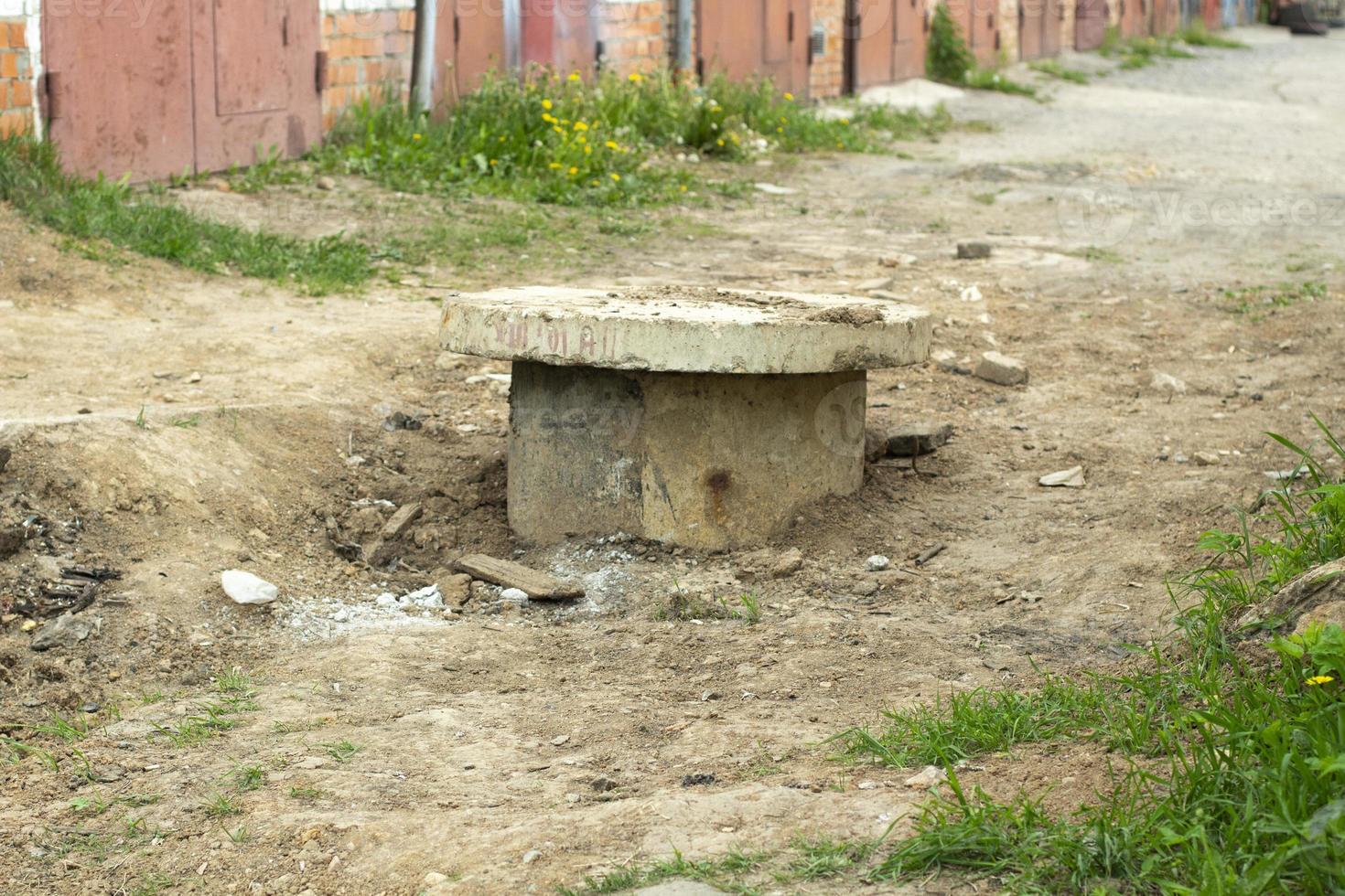 Old sewer in ground. Sewer hatch dug up. Excavated earth around concrete ring. photo