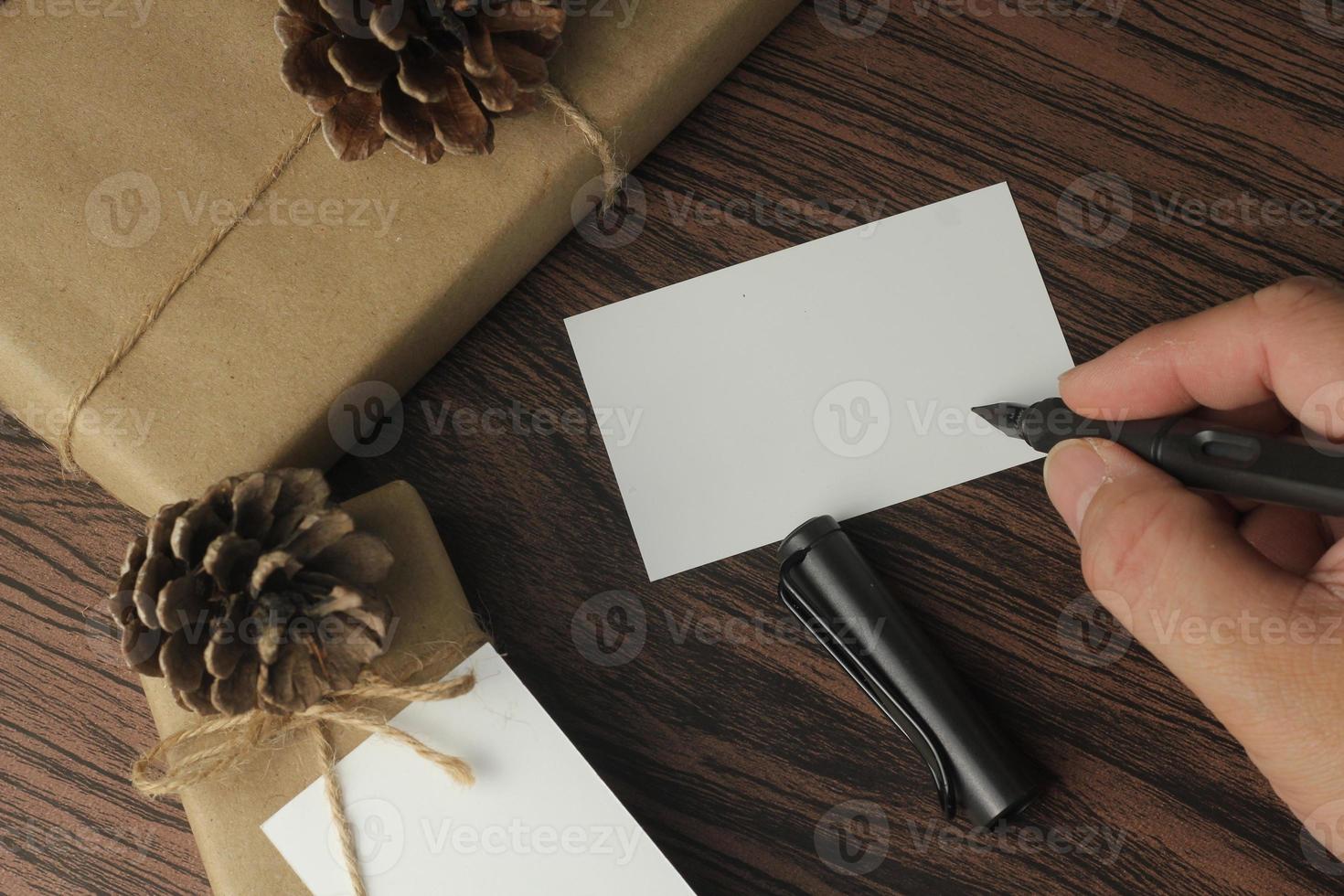 male hands wrapping new year gifts and writing cards On a brown wooden table, top view, flatlay photo