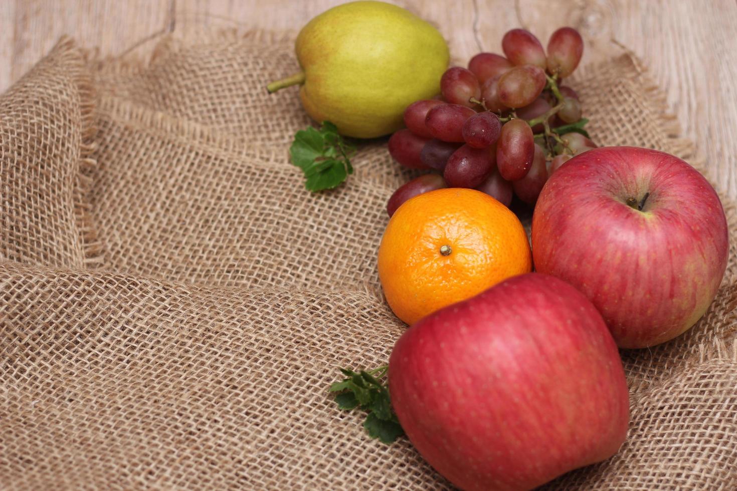 Fruits with vitamin C that are beneficial to the body. Place on sackcloth - orange, grape, apple, guava photo