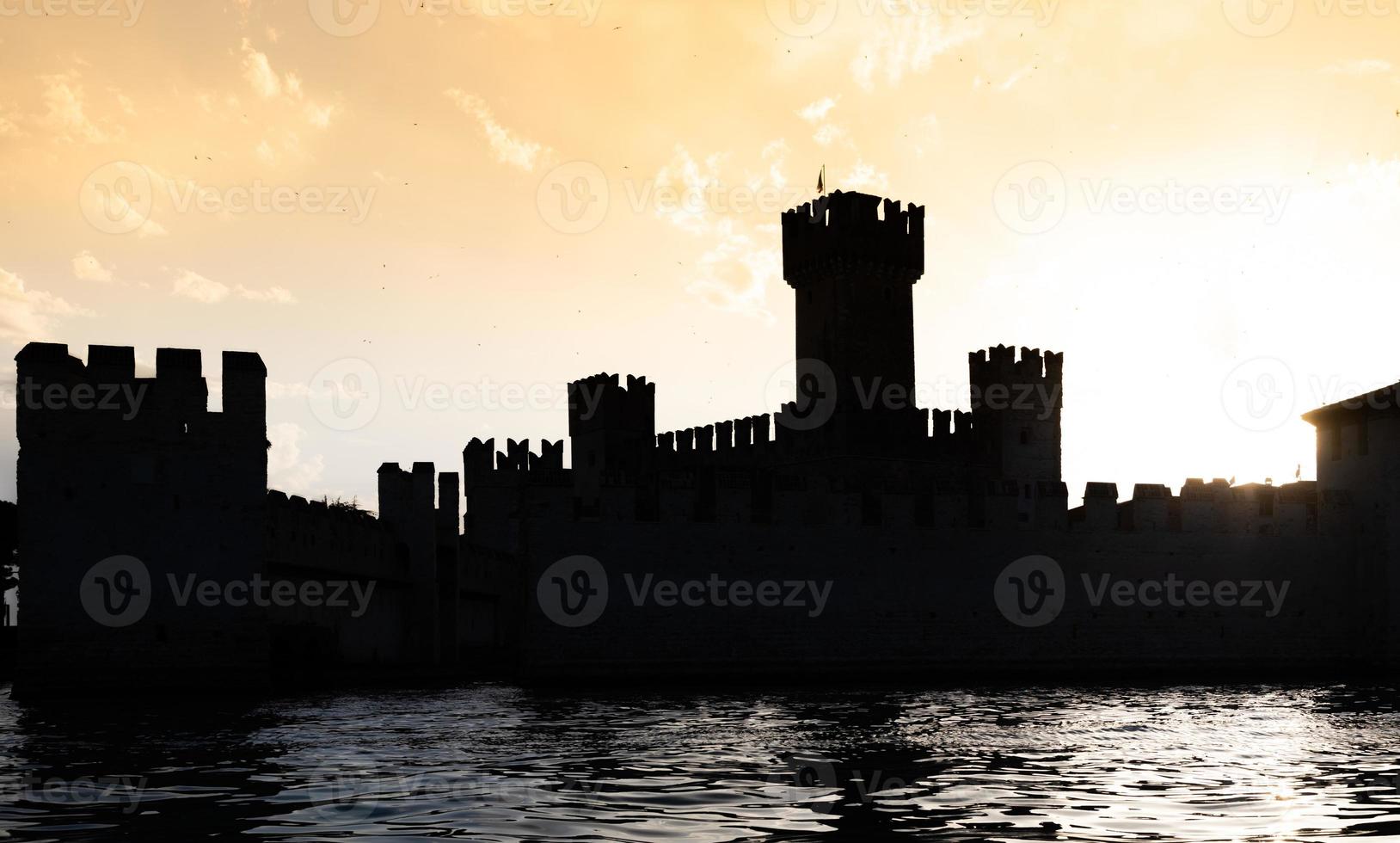 italia - silueta del castillo de sirmone en el lago de garda al atardecer. arquitectura medieval con torre. foto