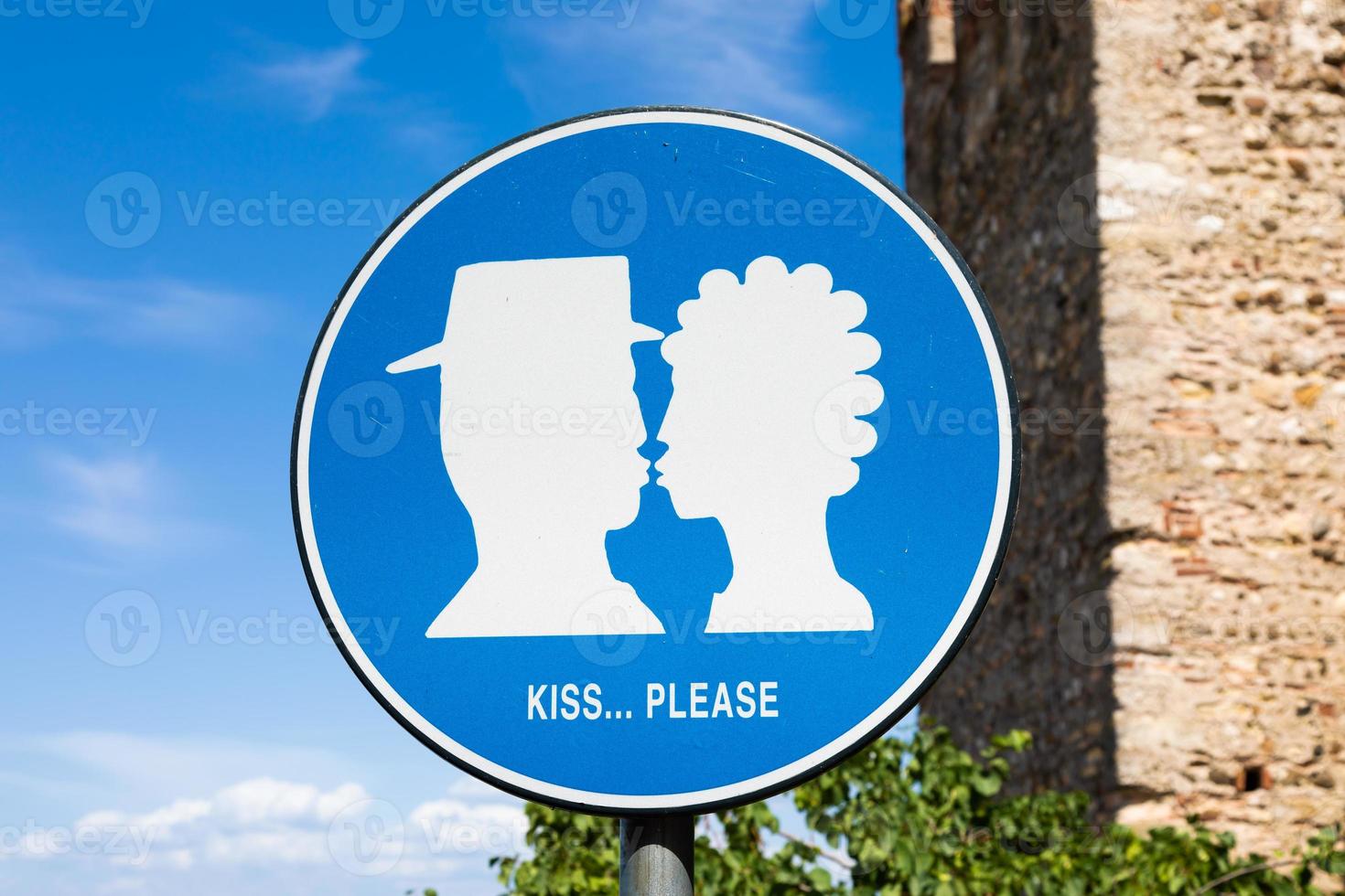 cartel de kiss street ubicado en un área pública frente al castillo de sirmione, italia. concepto de amor, pareja, romántico. foto