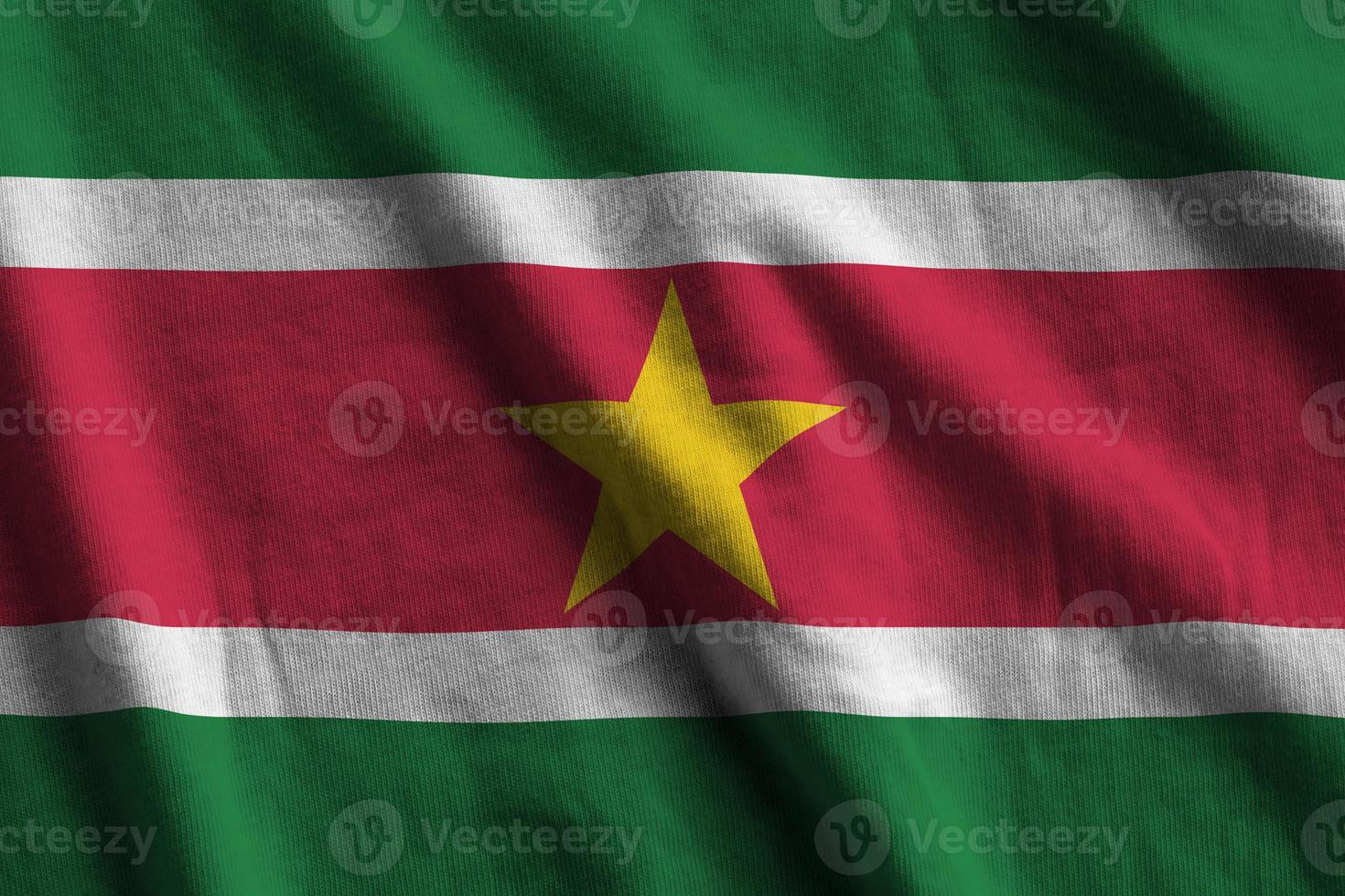 Suriname flag with big folds waving close up under the studio light indoors. The official symbols and colors in banner photo