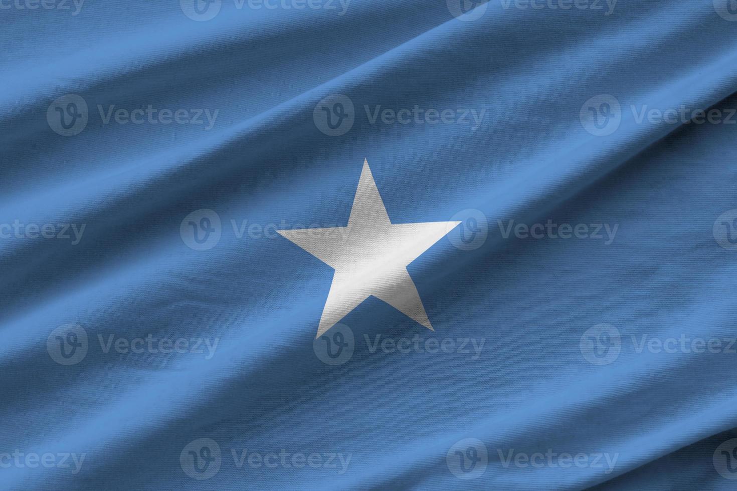Somalia flag with big folds waving close up under the studio light indoors. The official symbols and colors in banner photo