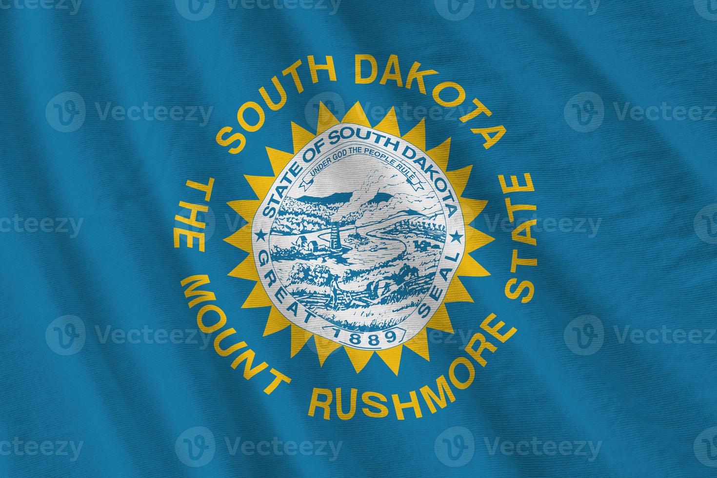 South Dakota US state flag with big folds waving close up under the studio light indoors. The official symbols and colors in banner photo