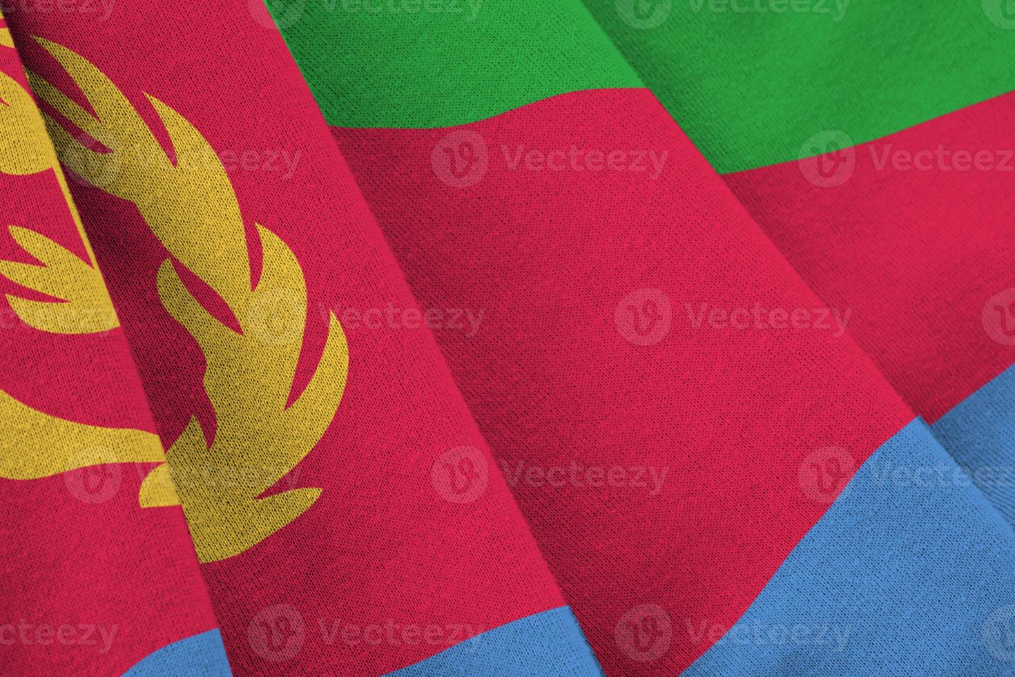 Eritrea flag with big folds waving close up under the studio light indoors. The official symbols and colors in banner photo