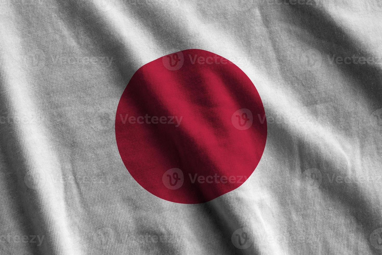 Japan flag with big folds waving close up under the studio light indoors. The official symbols and colors in banner photo