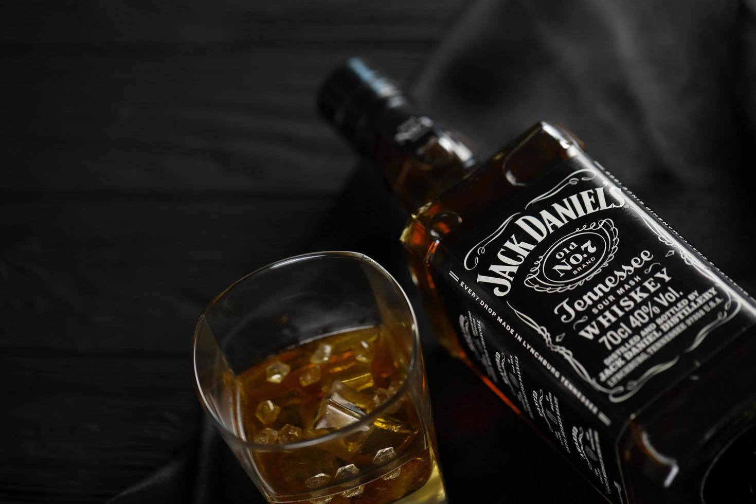 KYIV, UKRAINE - MAY 4, 2022 Jack Daniels original alcohol bottle on wooden table with black fabric photo