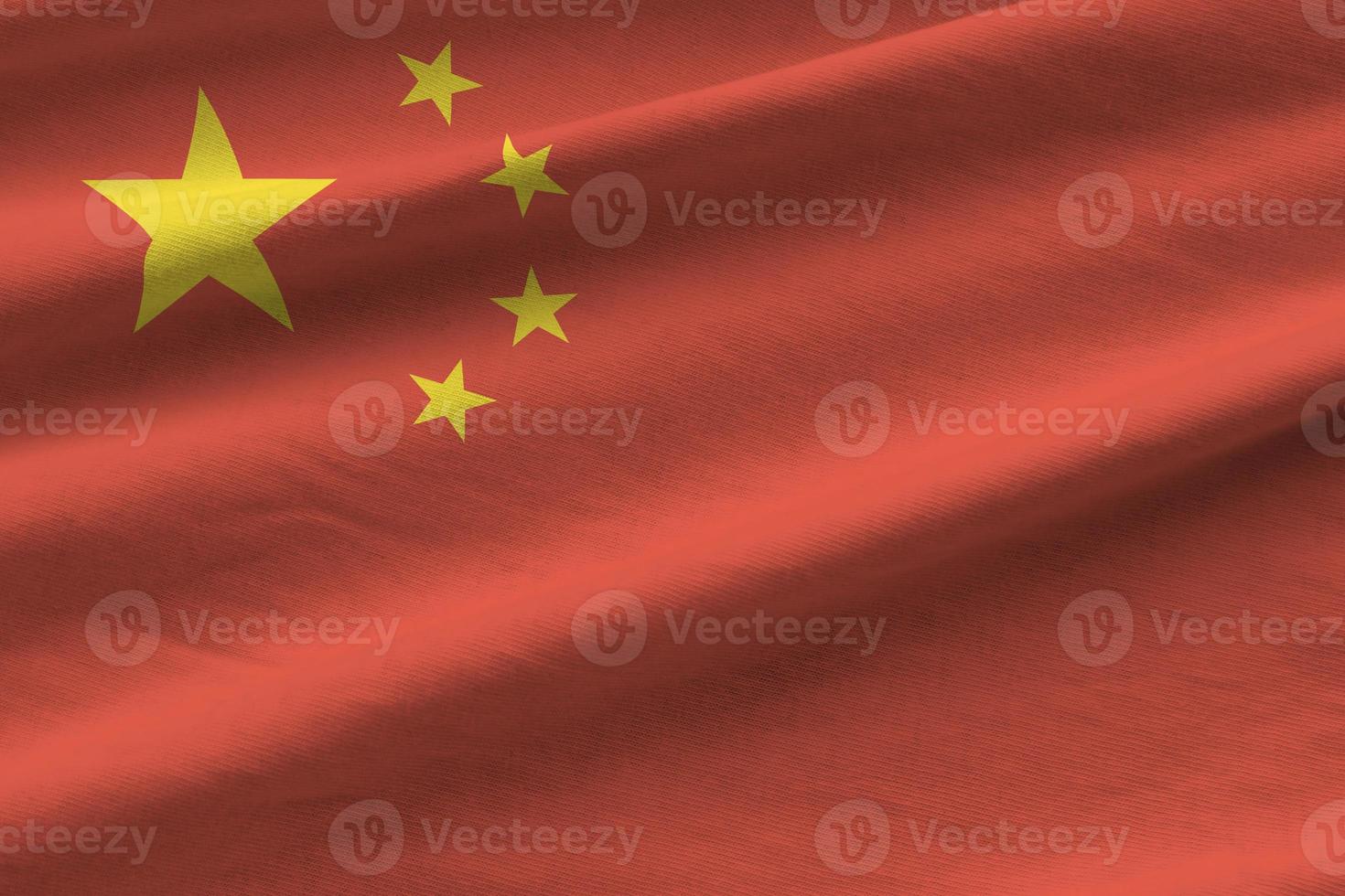 China flag with big folds waving close up under the studio light indoors. The official symbols and colors in banner photo