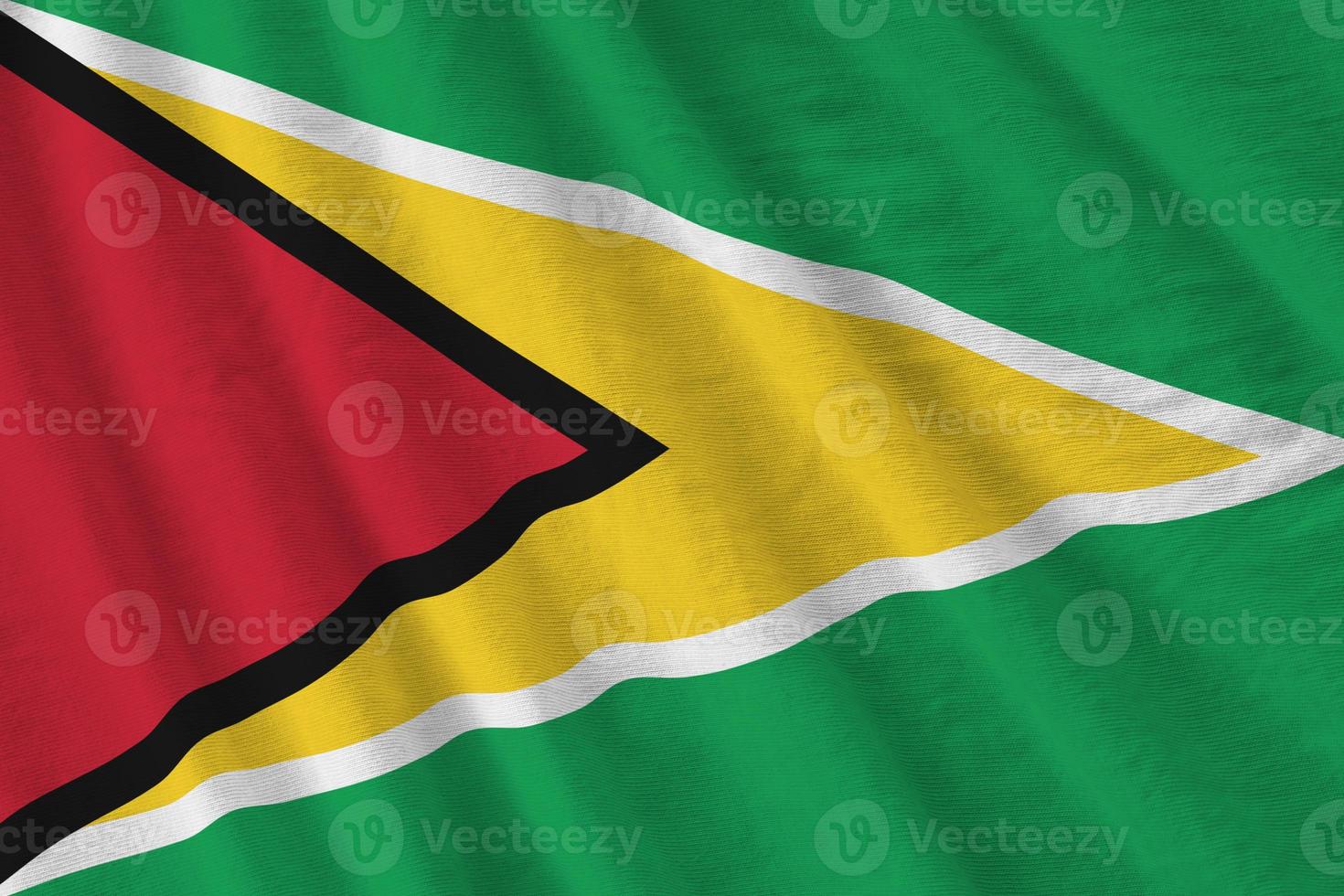 Guyana flag with big folds waving close up under the studio light indoors. The official symbols and colors in banner photo