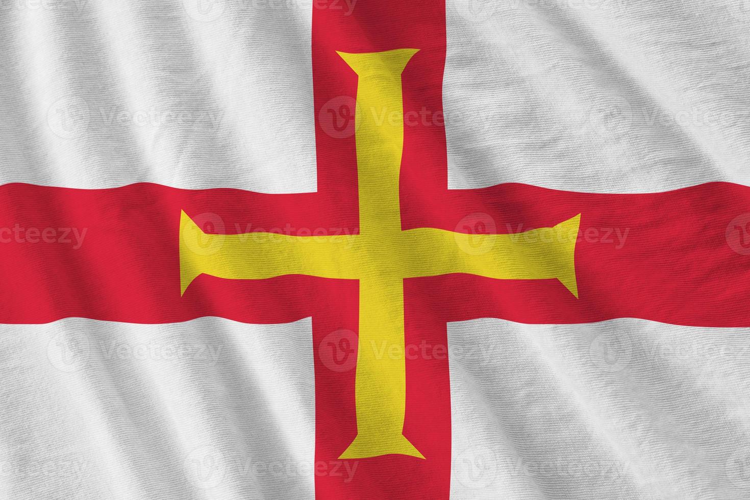 Guernsey flag with big folds waving close up under the studio light indoors. The official symbols and colors in banner photo