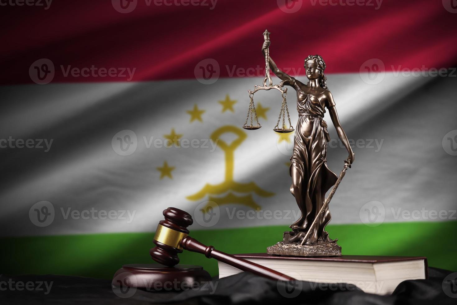 Tajikistan flag with statue of lady justice, constitution and judge hammer on black drapery. Concept of judgement and guilt photo