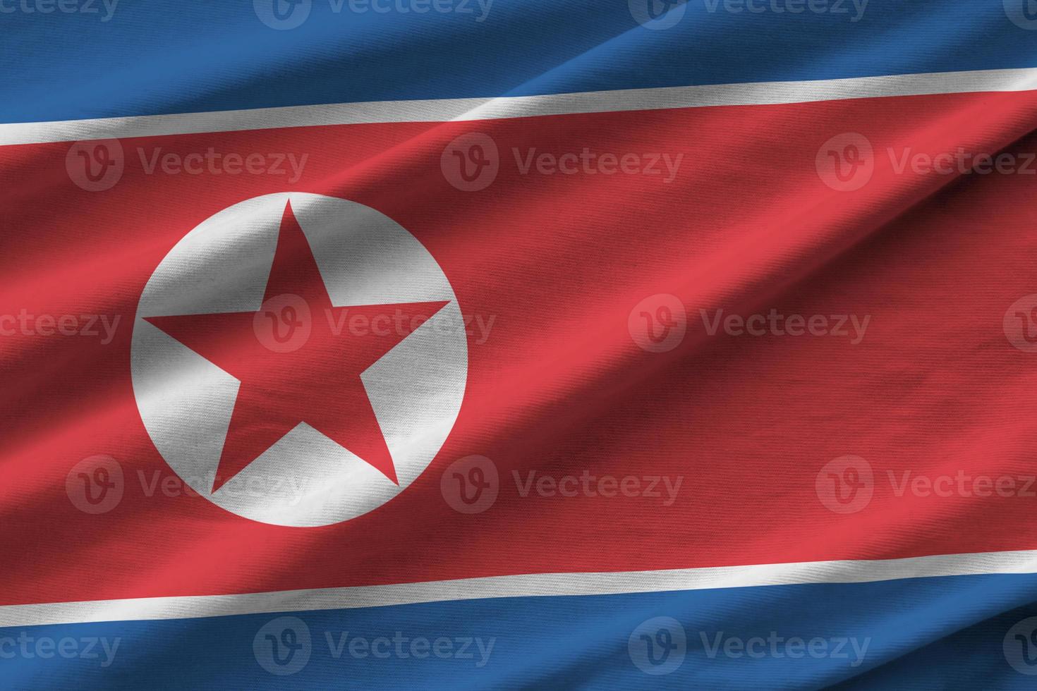 North Korea flag with big folds waving close up under the studio light indoors. The official symbols and colors in banner photo