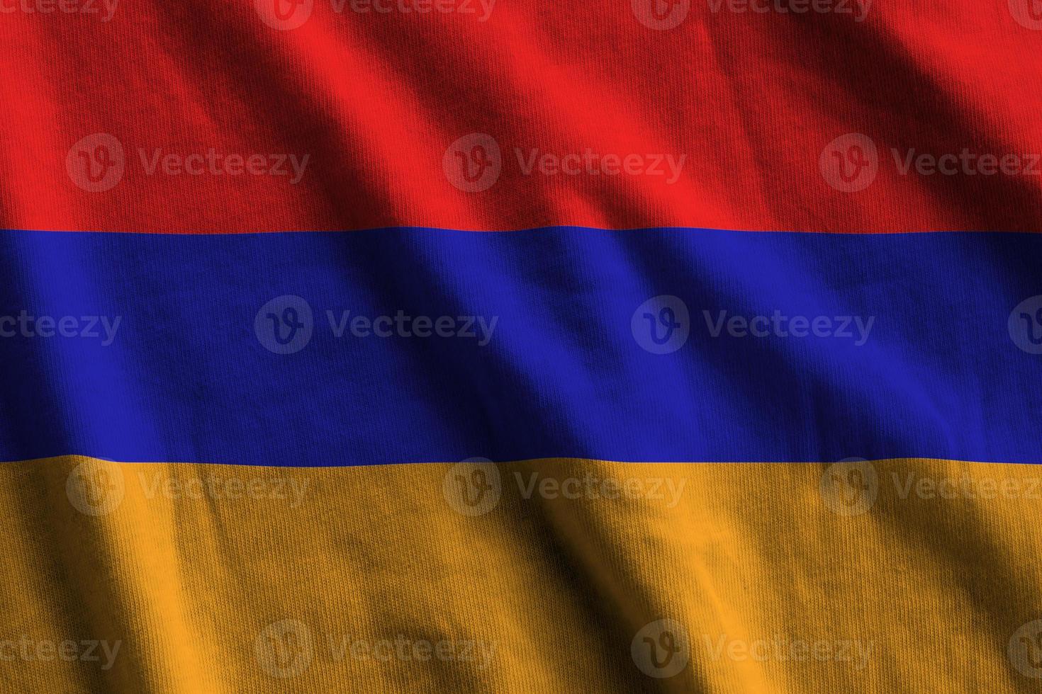 Armenia flag with big folds waving close up under the studio light indoors. The official symbols and colors in banner photo