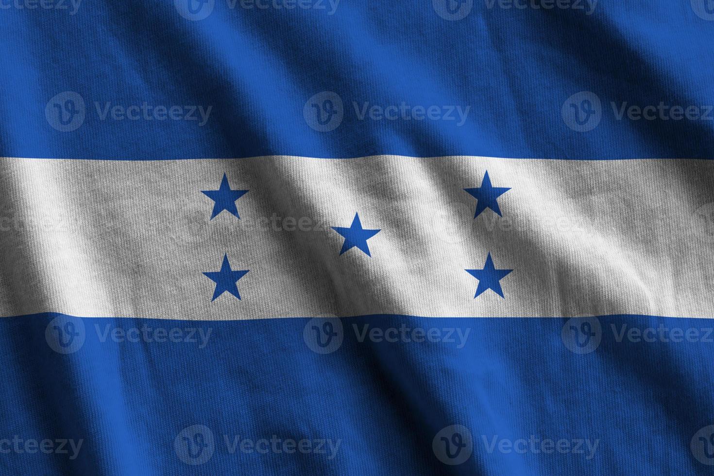 Honduras flag with big folds waving close up under the studio light indoors. The official symbols and colors in banner photo