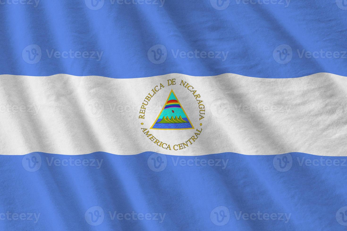 Nicaragua flag with big folds waving close up under the studio light indoors. The official symbols and colors in banner photo