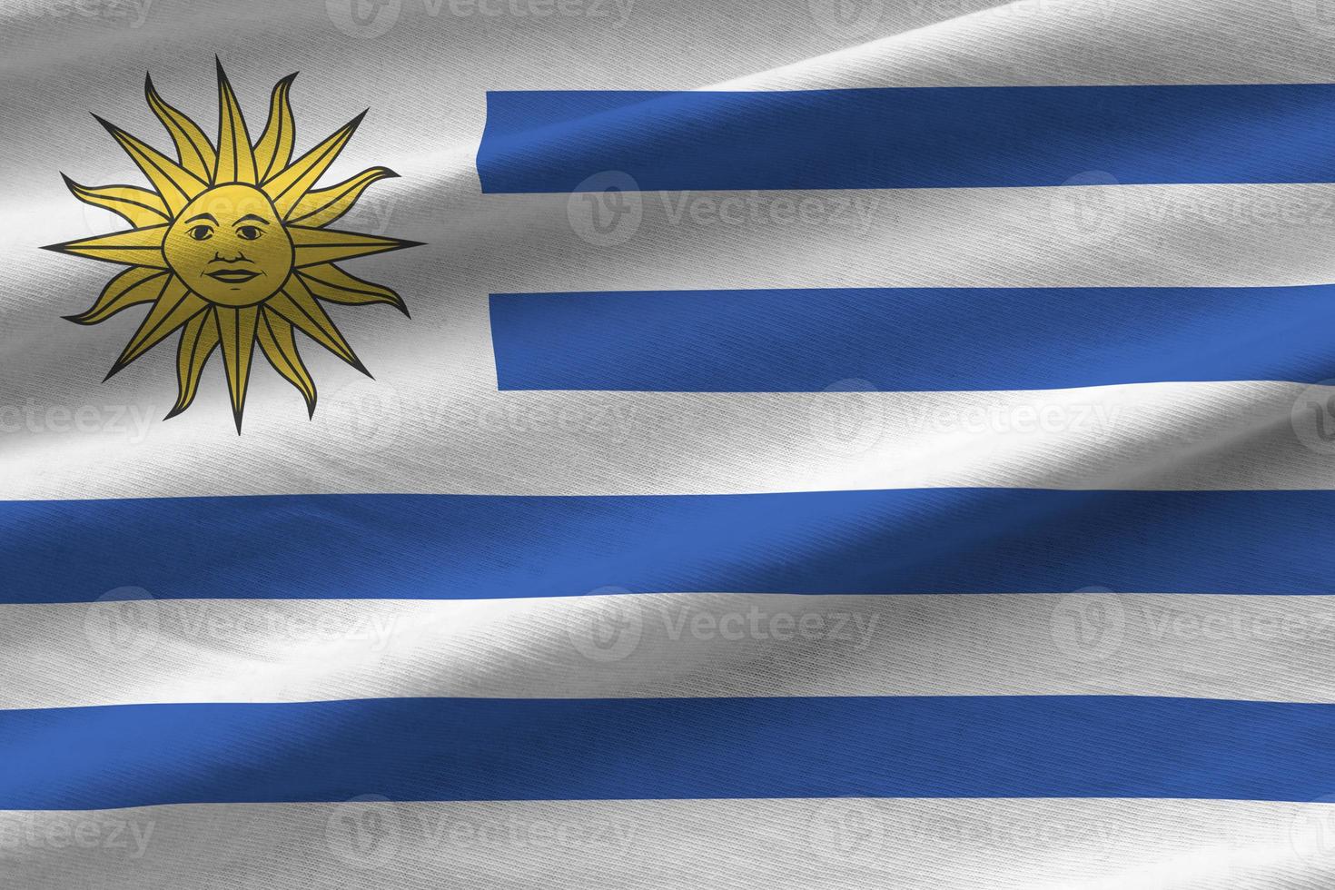 bandera de uruguay con grandes pliegues ondeando de cerca bajo la luz del estudio en el interior. los símbolos y colores oficiales en banner foto