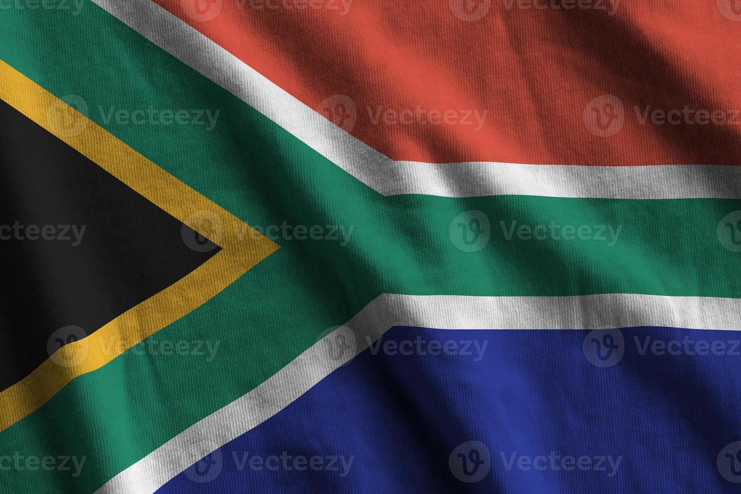 South Africa flag with big folds waving close up under the studio light indoors. The official symbols and colors in banner photo