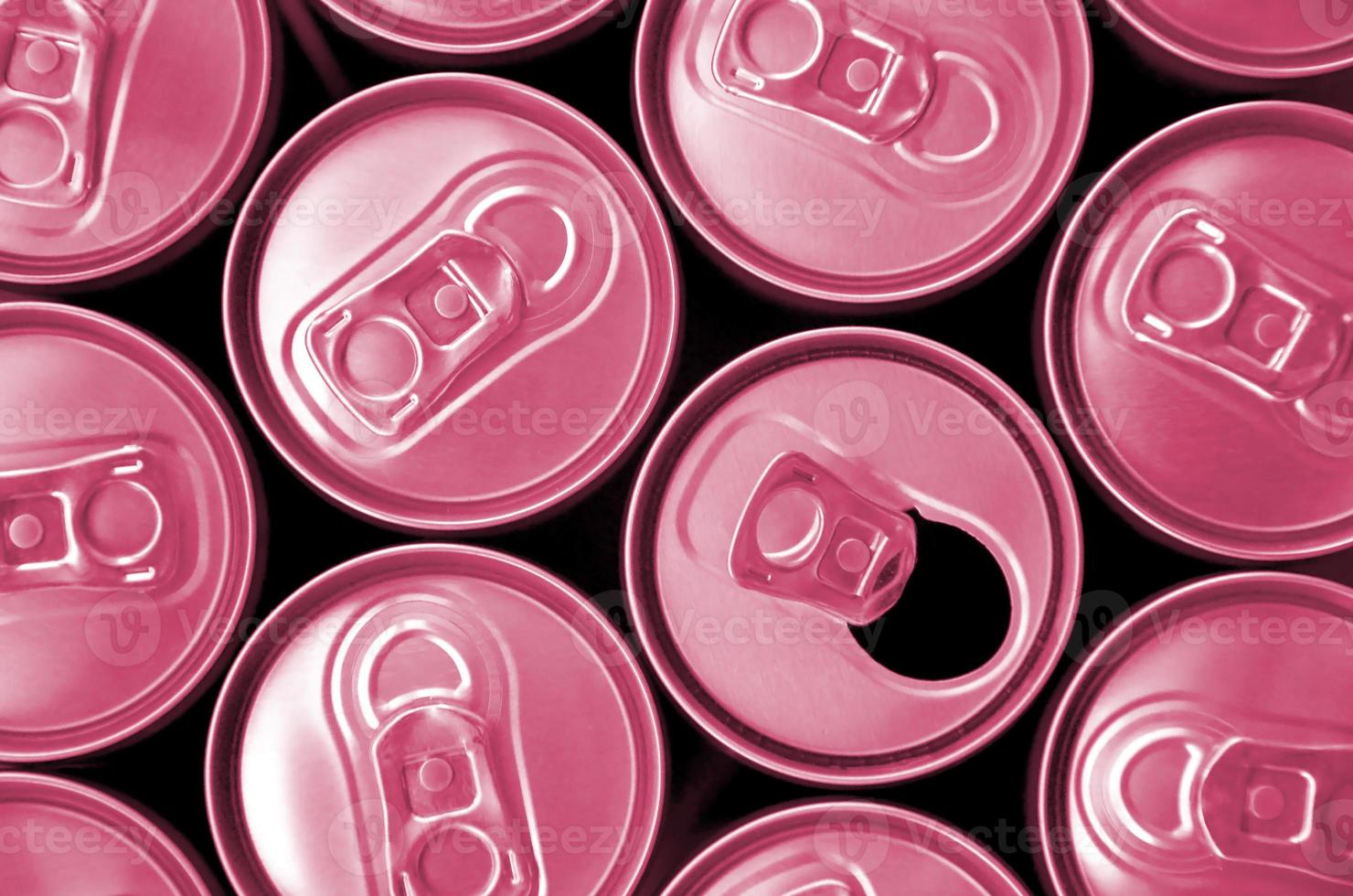 muchas latas de refrescos o envases de bebidas energéticas. muchas latas recicladas hechas de aluminio. imagen tonificada en viva magenta, color del año 2023 foto