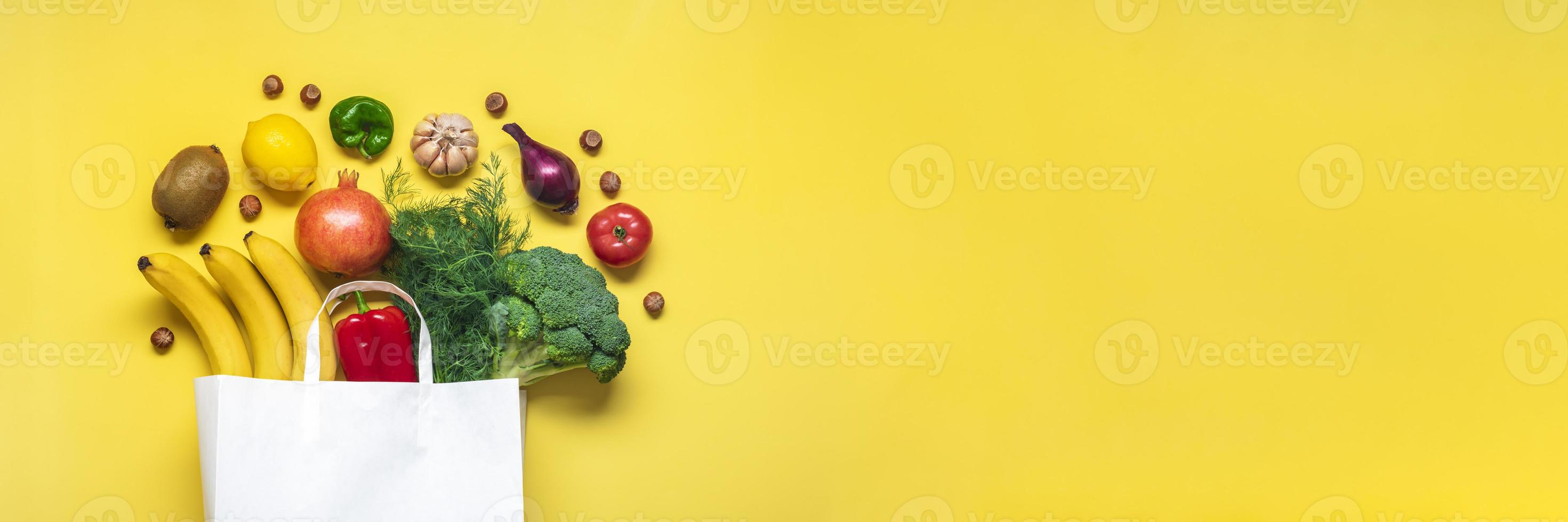 Eco friendly paper shop bag with raw organic green vegetables isolated on yellow background Flat lay, top view Zero waste, plastic free concept Healthy clean eating diet and detox, agriculture concept photo