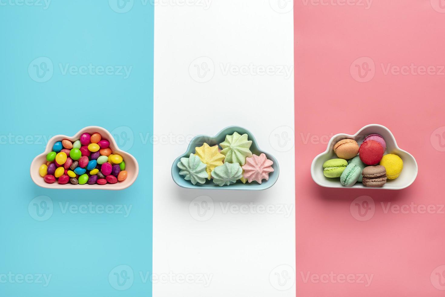 Caramelos coloridos: piruletas, merengues, macarrones en un tazón en forma de nube aislado en rosa, blanco, fondo azul plano vista superior knolling comida poco saludable y sabrosa concepto creativo tarjeta de vacaciones foto