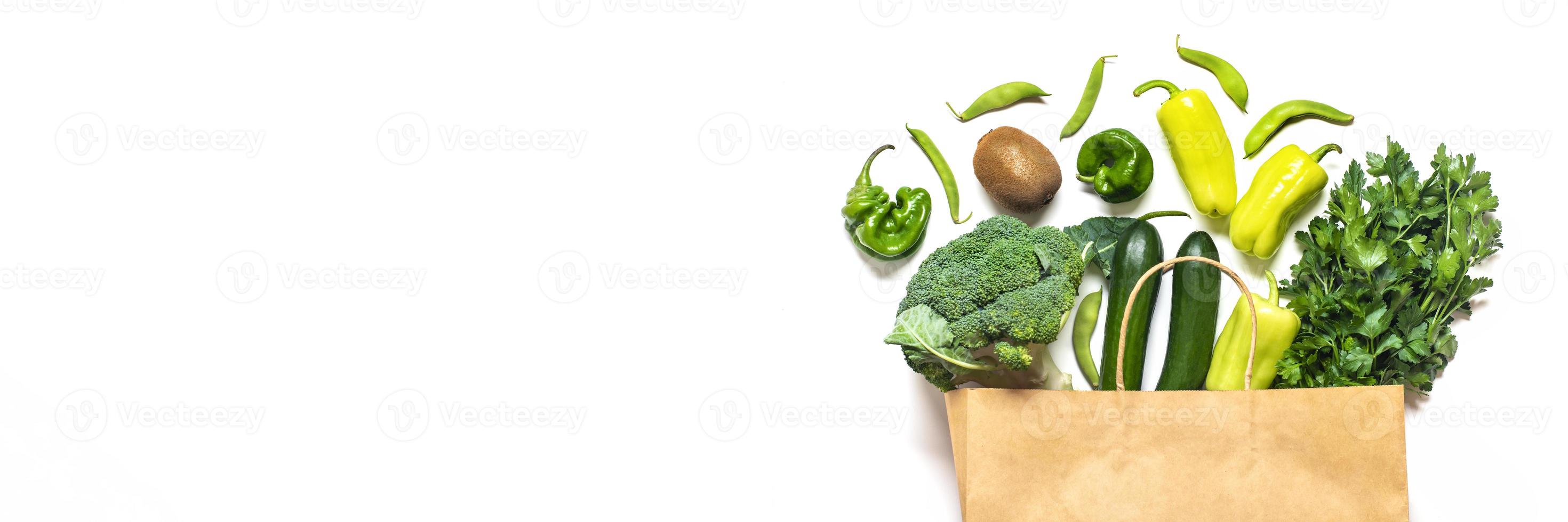 Eco friendly paper shop bag with raw organic green vegetables isolated on white background Flat lay, top view Zero waste, plastic free concept Healthy clean eating diet and detox, agriculture concept photo