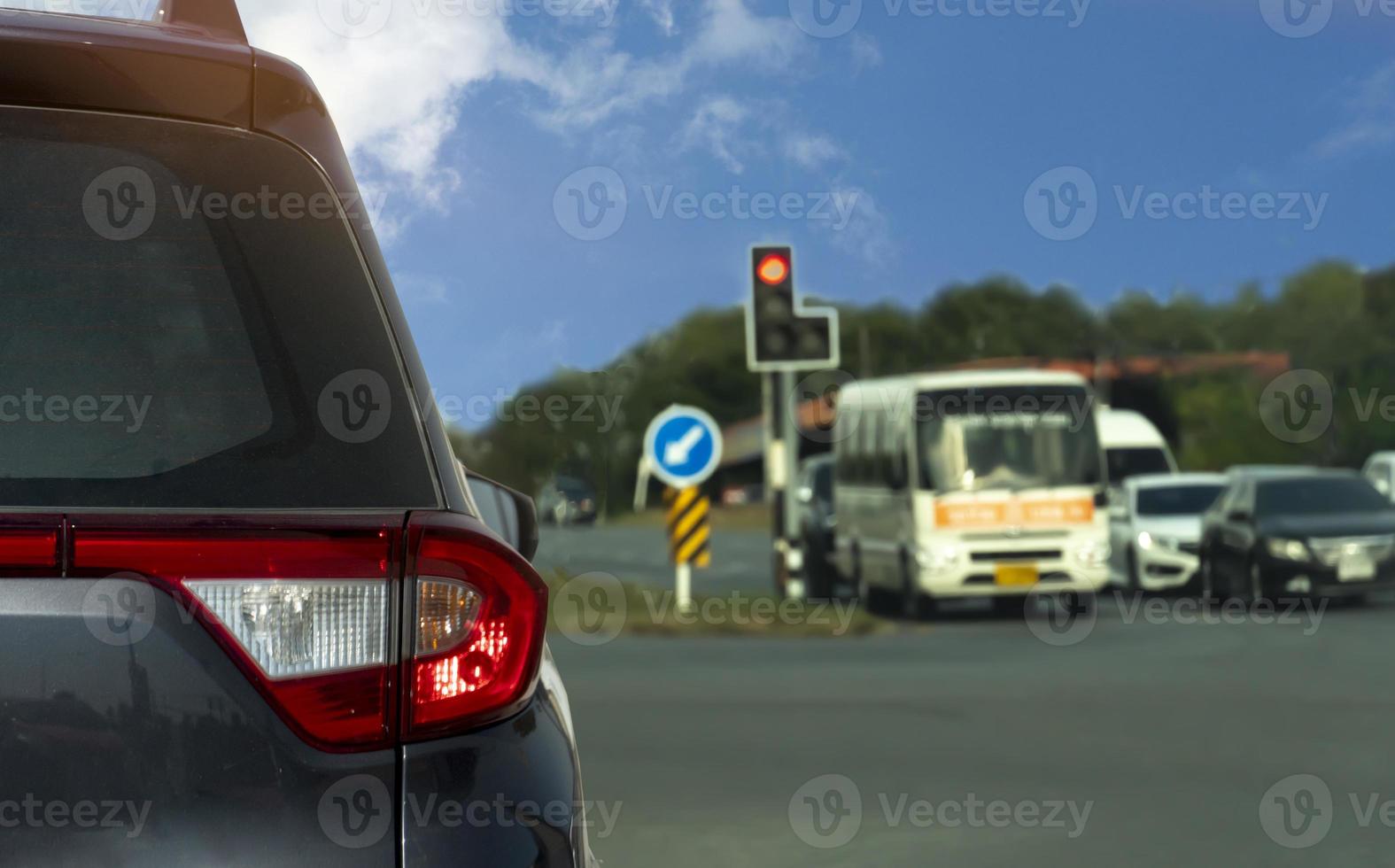 Rear side of car driving on the asphalt road. Stop and open turn on light brake by traffic light signal. Blurred of other cars in the upcountry with trees. photo