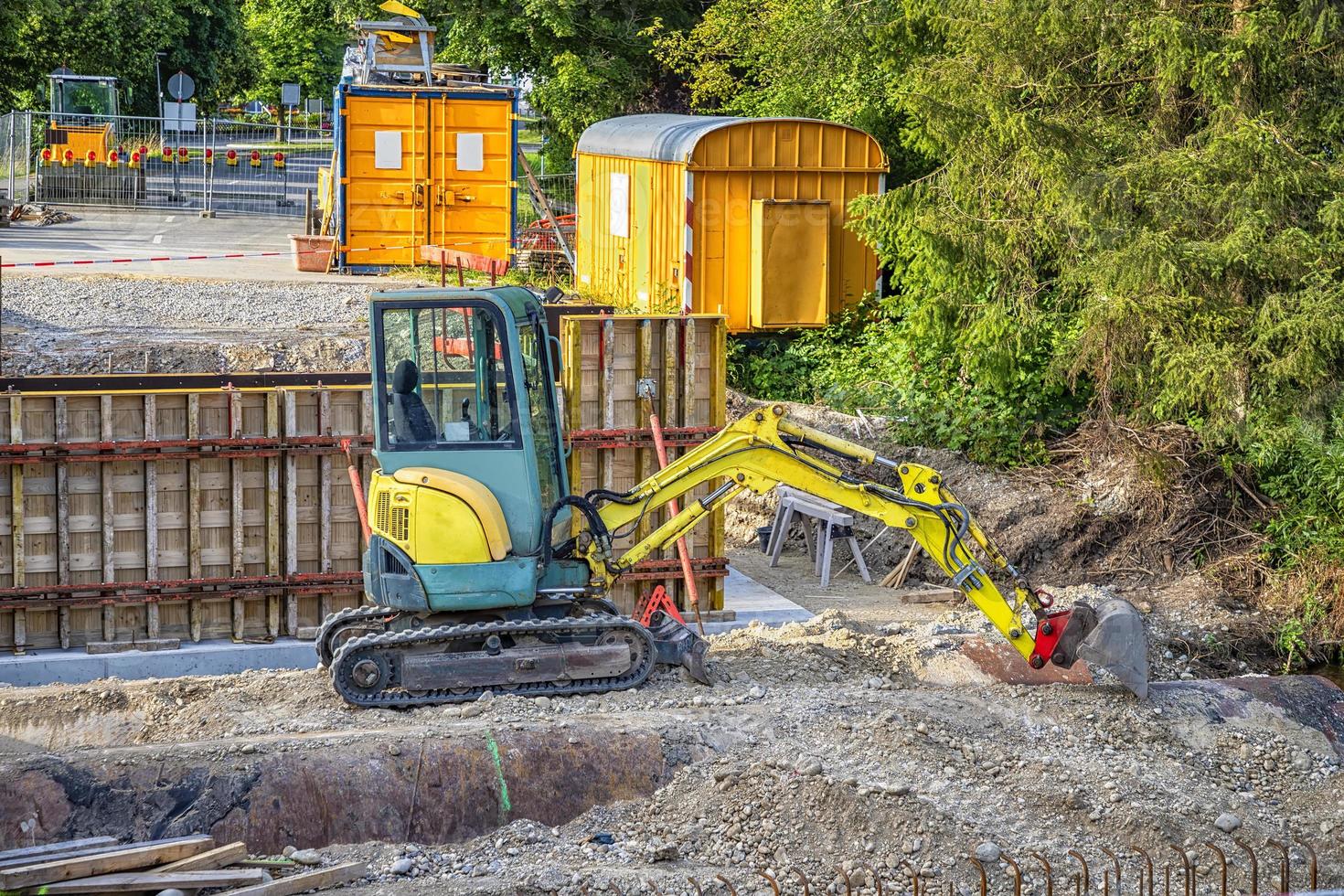 Small stopped excavator with a shovel and building site containers at the construction site photo