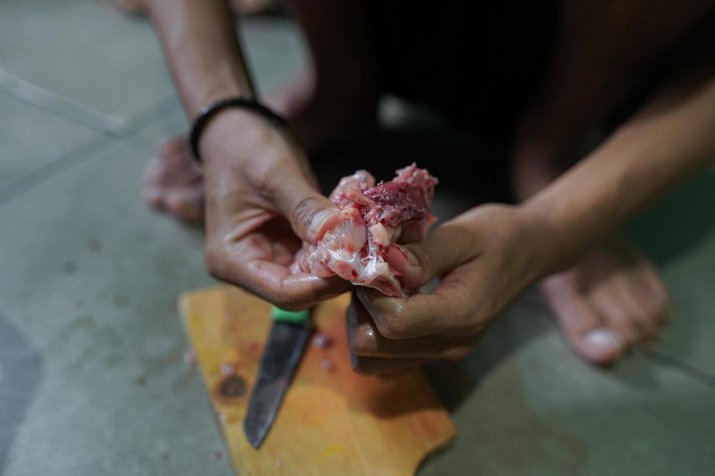 Fresh chicken meat is cut on a cutting board in a traditional market photo