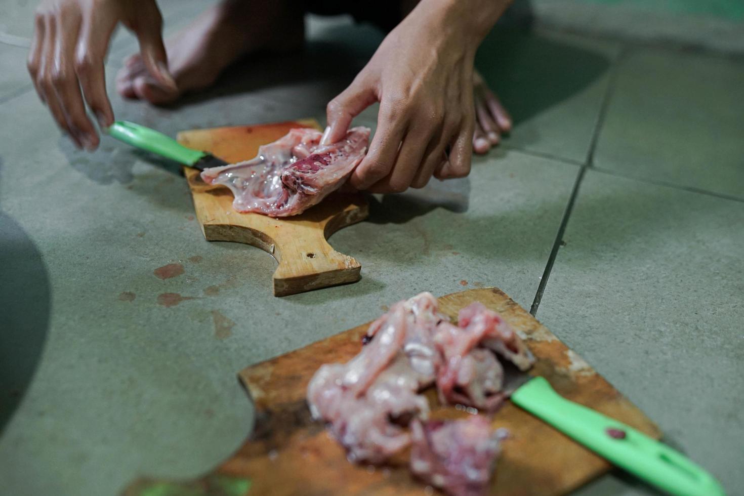 Fresh chicken meat is cut on a cutting board in a traditional market photo