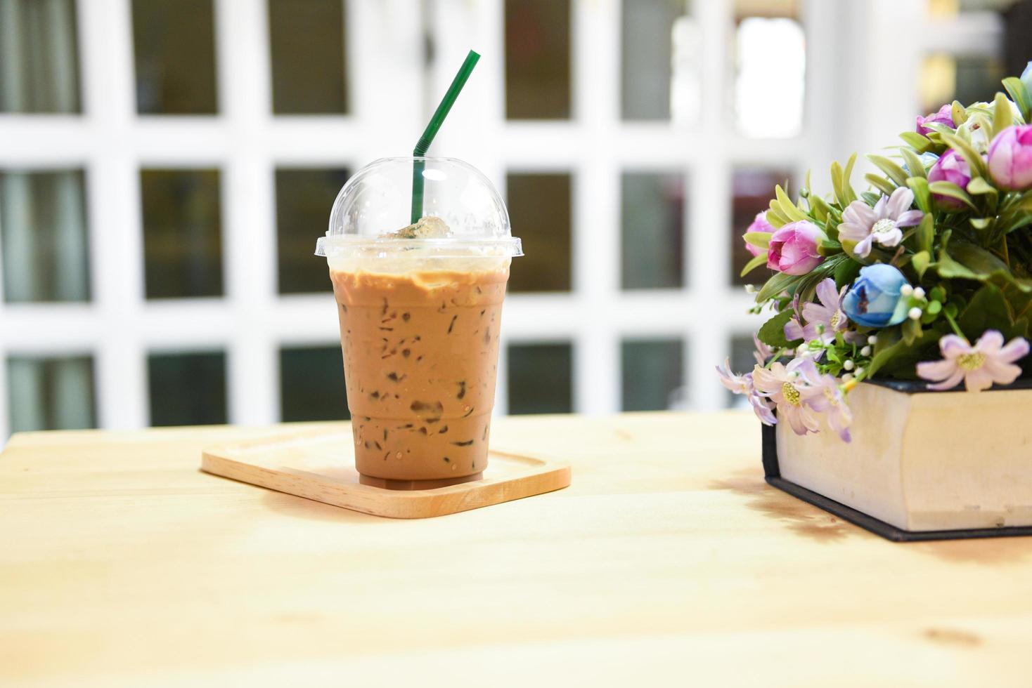 coffee plastic cup on wooden table background - plastic glass of iced coffee with milk photo