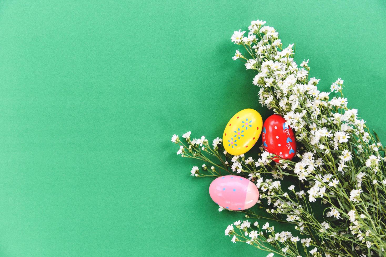 Easter eggs decoration white cutter flower on green background - top view photo
